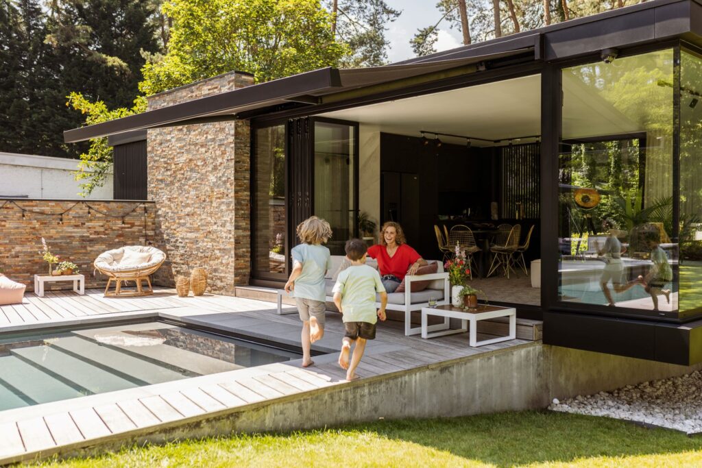 Dina Tersago onder een Harol zonneluifel met kinderen die naar haar toe lopen